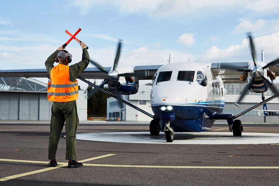 Fotografia biznesowa Rzeszów - Pilot na lotnisku kieruje samolotem z użyciem chorągiewek.